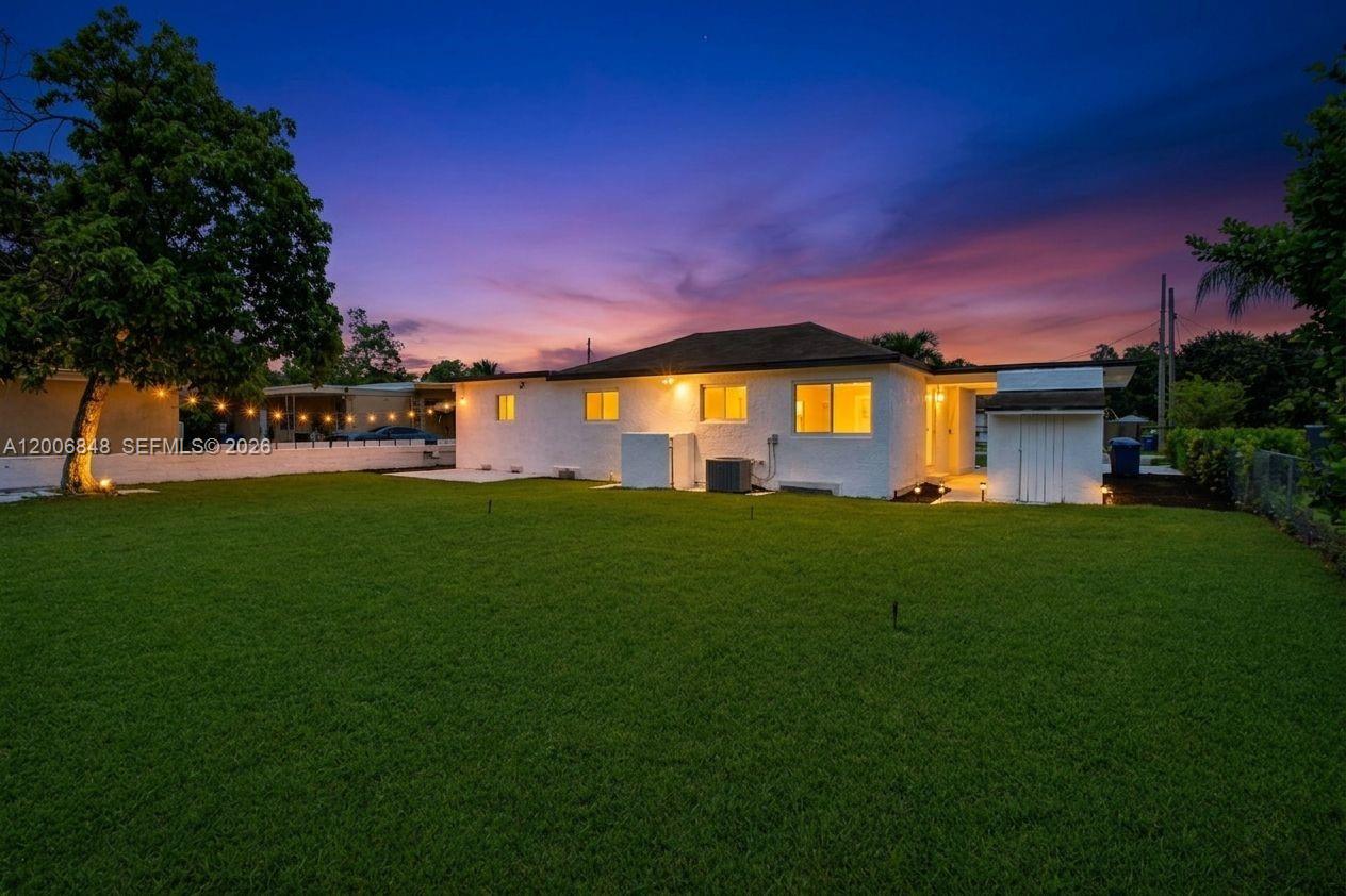 The exterior of a white single-story house with a large lawn at sunset — 2870 NW 169th Ter, Miami Gardens FL 33056, MIAMI GARDENS, FL