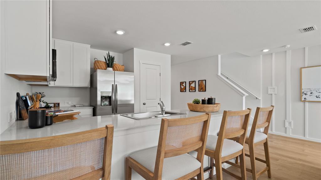 A modern kitchen features white cabinets, stainless steel appliances, a quartz island, and wooden barstools — 3314 WANDEL TERRACE, DAVENPORT, FL