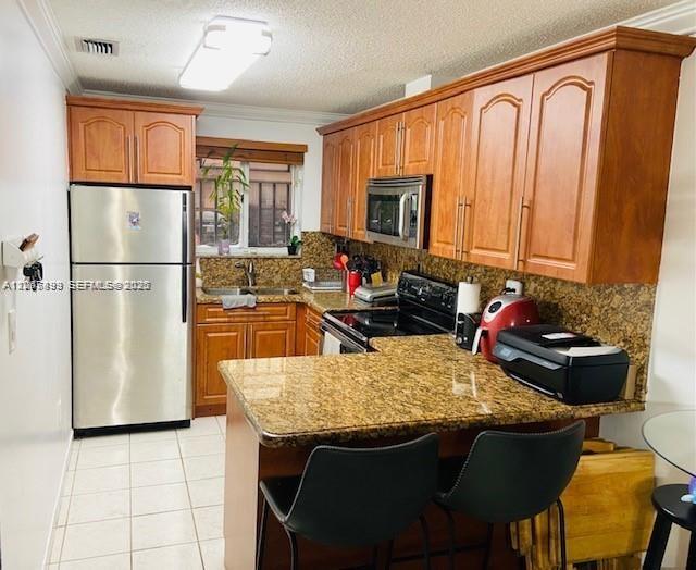 A kitchen features wood cabinets, granite countertops, a stainless steel refrigerator, and a breakfast bar — 8075 NW 8th St # 6, Miami FL 33126, MIAMI, FL