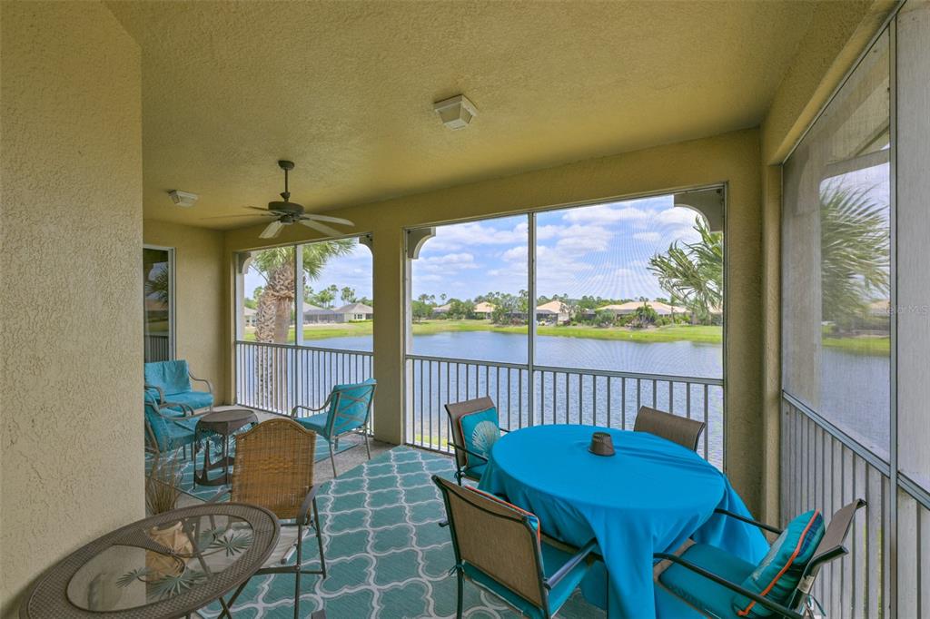A screened-in patio with outdoor furniture overlooks a lake and residential neighborhood — 1330 EMERALD DUNES DRIVE, SUN CITY CENTER, FL