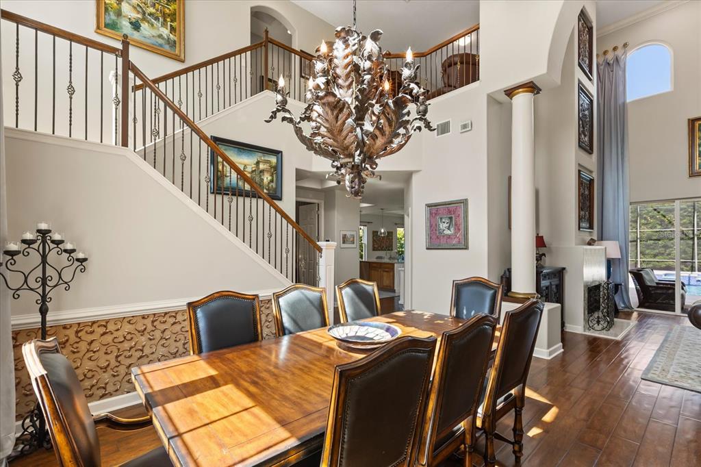A dining room with a large wooden table, leather chairs, and a grand metal chandelier — 1554 LAKE RHEA DRIVE, WINDERMERE, FL