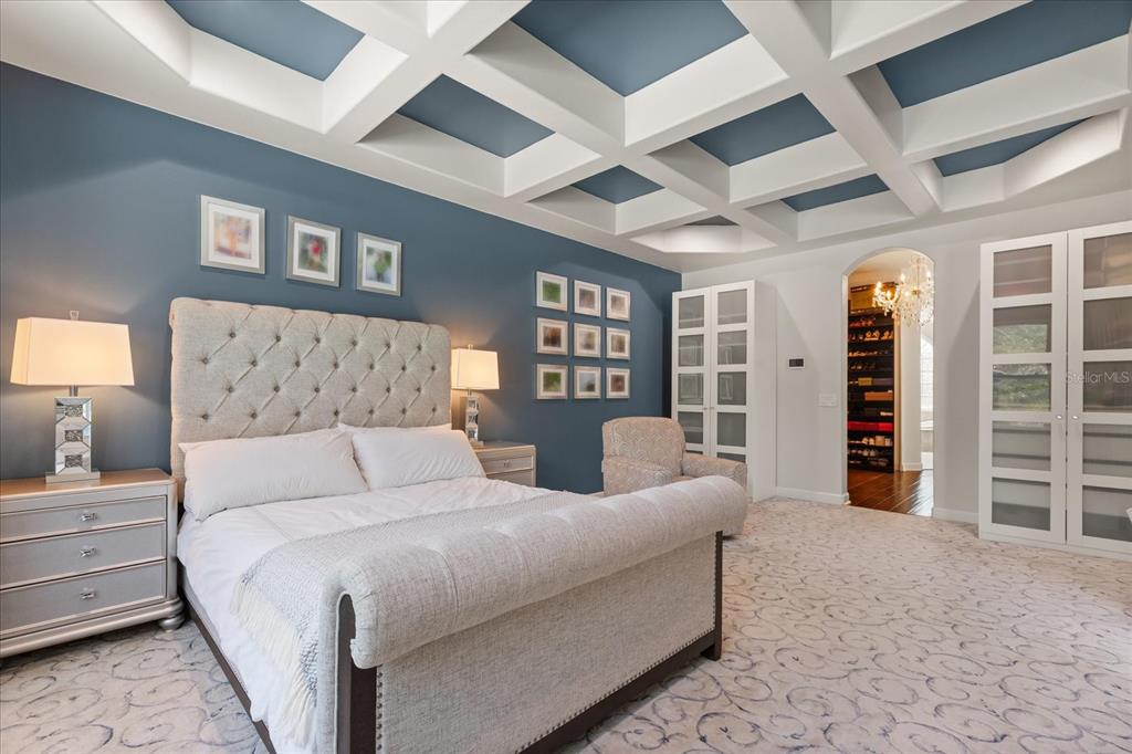 A bedroom features a tufted headboard, blue accent wall, coffered ceiling, and patterned carpet — 1554 LAKE RHEA DRIVE, WINDERMERE, FL