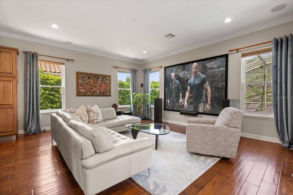 A living room features a large projection screen, white leather sectional, and hardwood flooring — 1554 LAKE RHEA DRIVE, WINDERMERE, FL