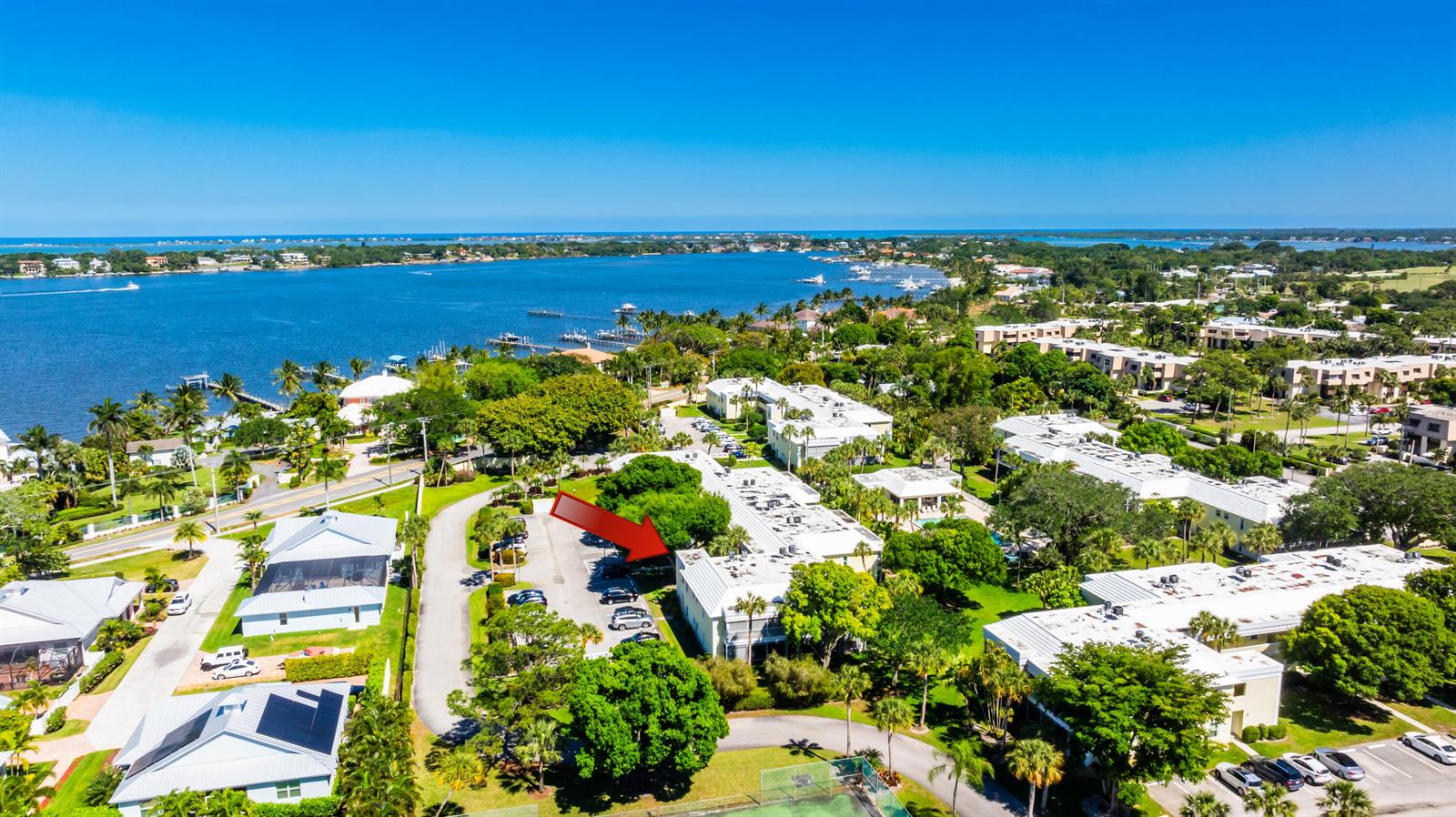 An aerial view shows a multi-story residential building complex surrounded by trees near a bay — 1600 SE Saint Lucie Boulevard # 205, Stuart FL 34996, STUART, FL
