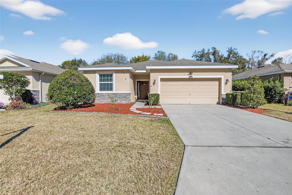 A single-story suburban house with a tan stucco exterior, stone accents, and a concrete driveway — 2819 HOLLY BLUFF COURT, PLANT CITY, FL
