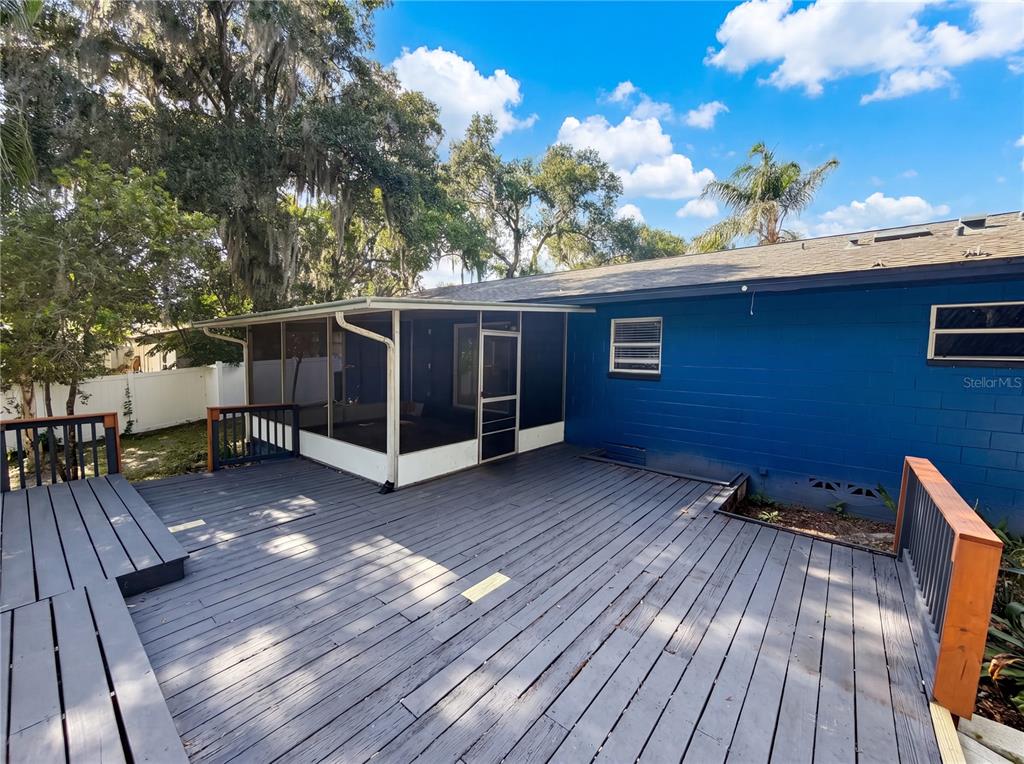 A blue house exterior features a large wooden deck and an attached screened-in porch — 820 E WISCONSIN AVENUE, DELAND, FL