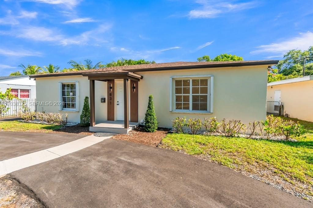 A single-story house with a beige exterior, a small covered entryway, and a paved driveway — 831 NE 128th St, North Miami FL 33161, NORTH MIAMI, FL