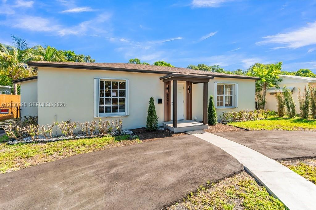 A single-story house with a beige exterior, a dark roof, and a small covered entryway — 831 NE 128th St, North Miami FL 33161, NORTH MIAMI, FL