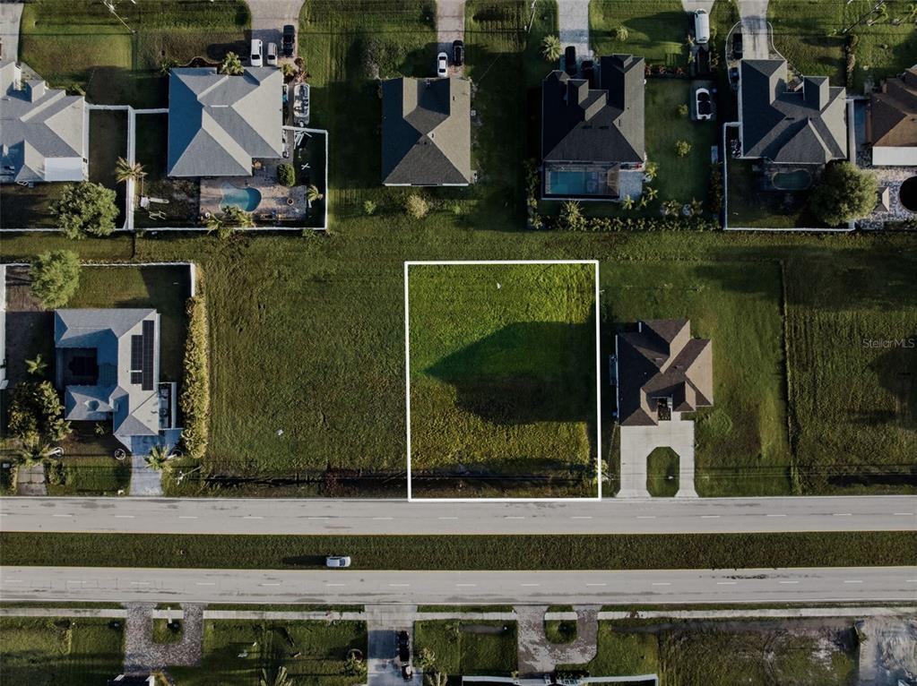 An aerial view shows a vacant rectangular residential lot situated between two houses — 2623 TROPICANA PARKWAY W, CAPE CORAL, FL