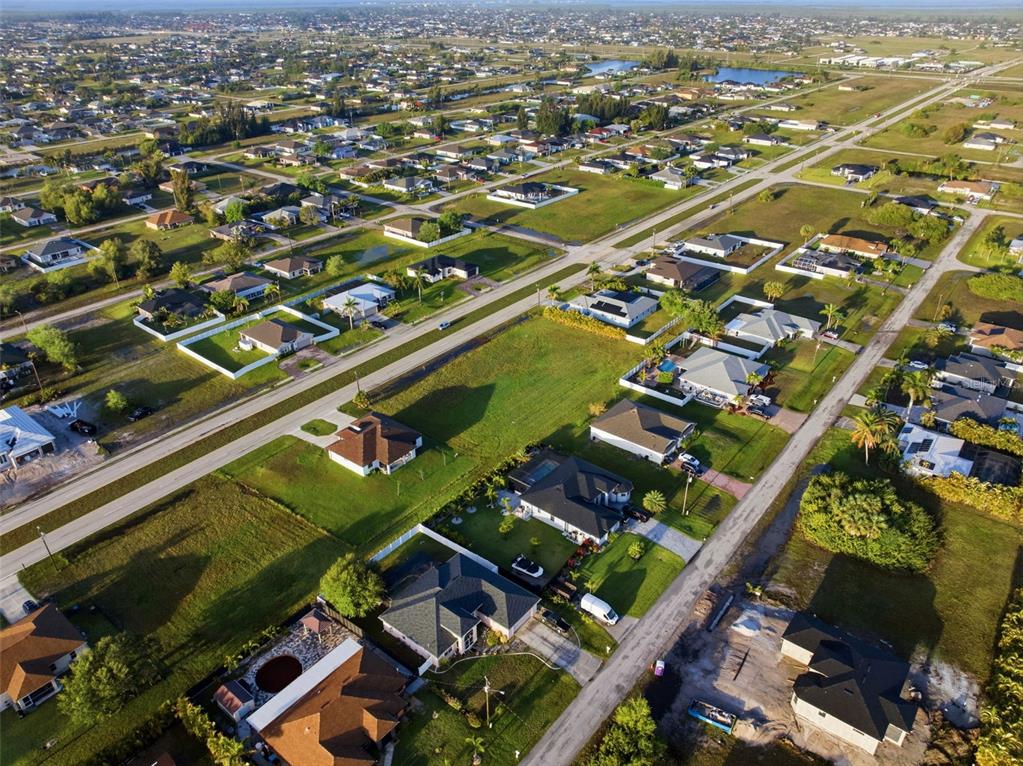 An aerial view shows a suburban neighborhood with houses, roads, and vacant lots — 2623 TROPICANA PARKWAY W, CAPE CORAL, FL