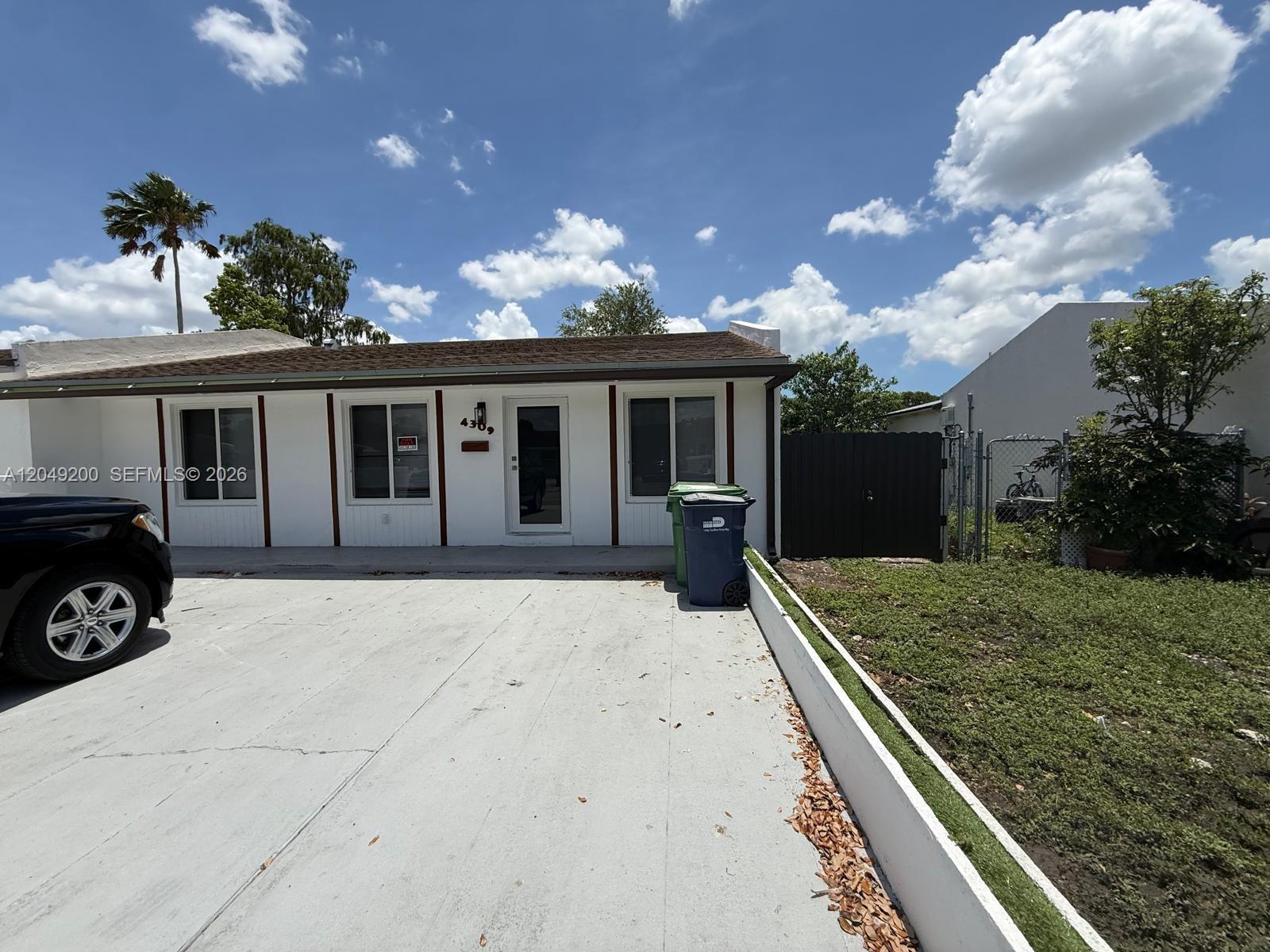 An open-concept kitchen and living area features white cabinetry, tile flooring, and a glass door — 4309 SW 129th Ave, Miami FL 33175, MIAMI, FL