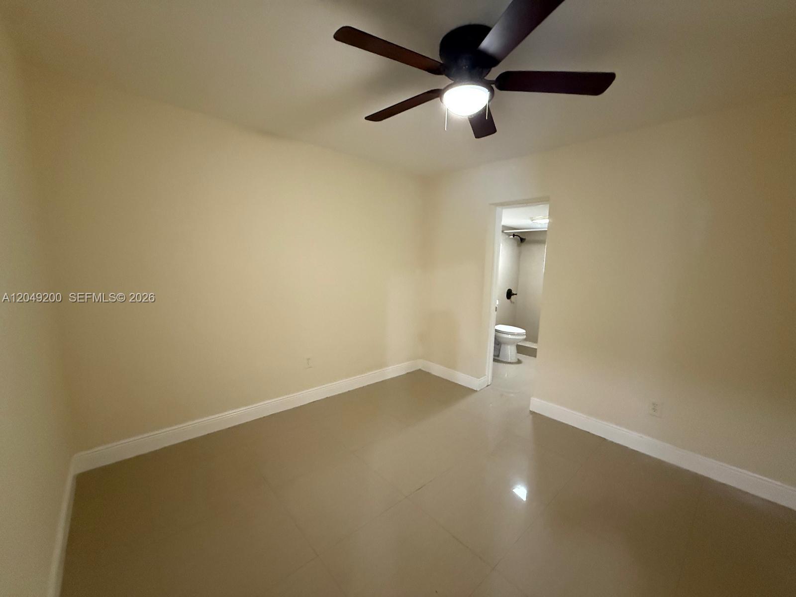 A kitchen features white cabinets, stainless steel appliances, dark countertops, and light tile flooring — 4309 SW 129th Ave, Miami FL 33175, MIAMI, FL