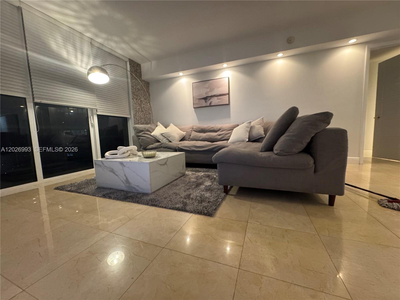 A living room features a gray sectional sofa, a marble coffee table, and tile flooring — 1830 S Ocean Dr # 3003, Hallandale Beach FL 33009, HALLANDALE BEACH, FL