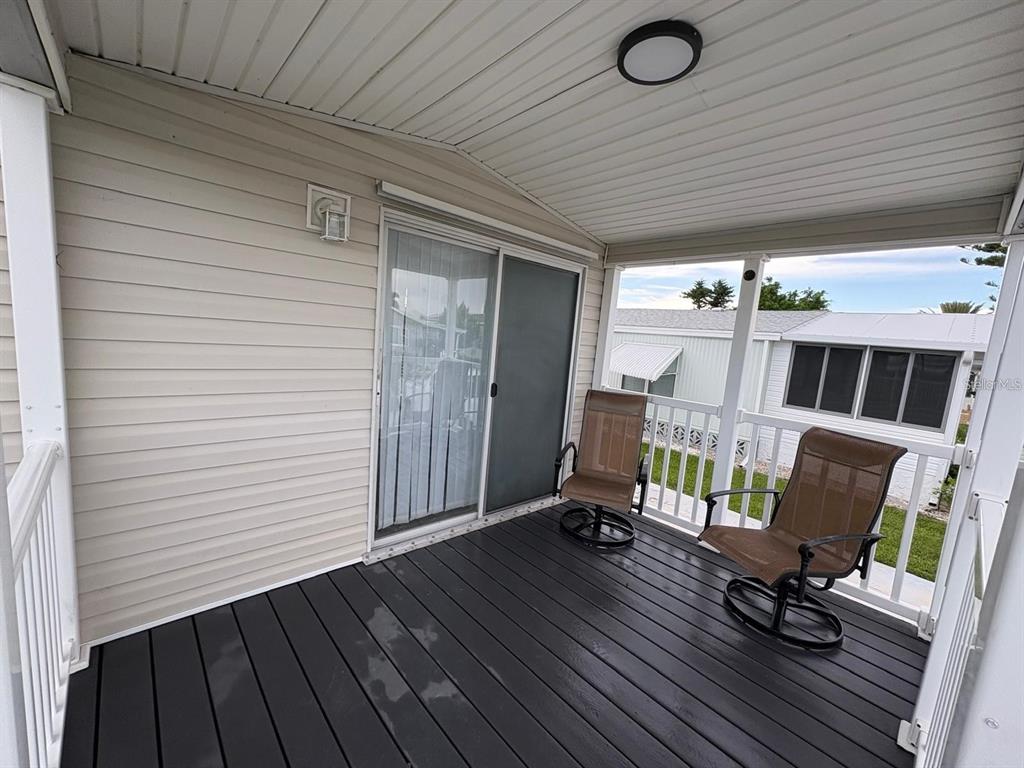 A covered porch features dark wood decking, two swivel chairs, and a sliding glass door — 653 LOS ALTOS, NORTH PORT, FL