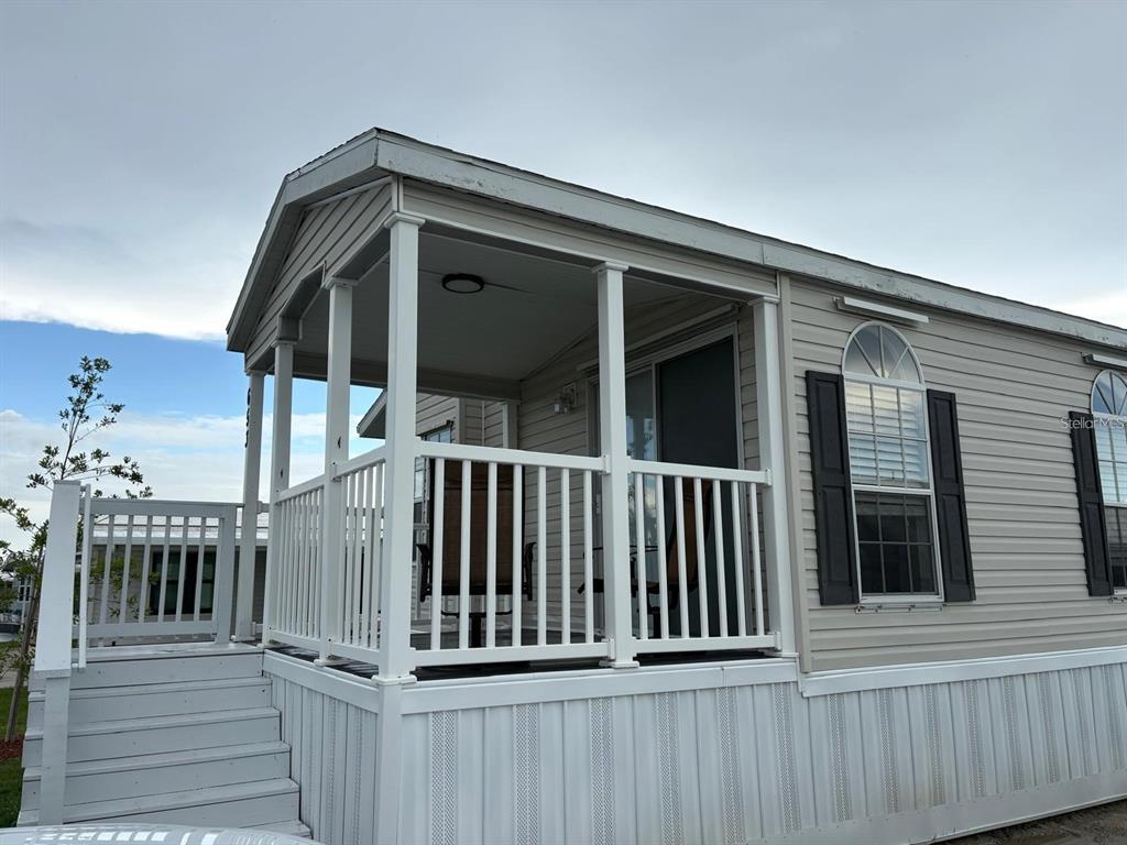A manufactured home exterior features a covered front porch with white railings and stairs — 653 LOS ALTOS, NORTH PORT, FL