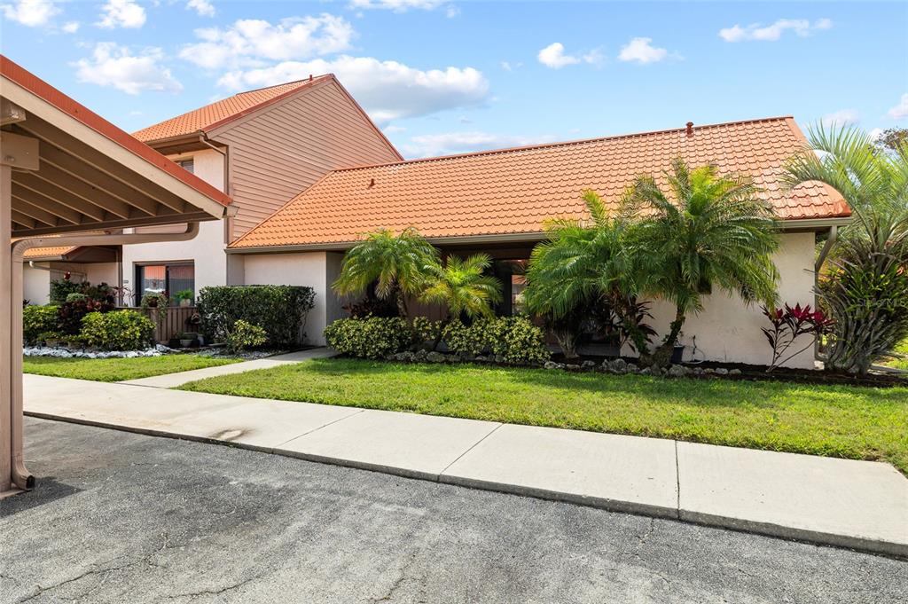 A single-story residential building with a terracotta tile roof and palm trees in front — 6535 DRAW LANE UNIT 85, SARASOTA, FL