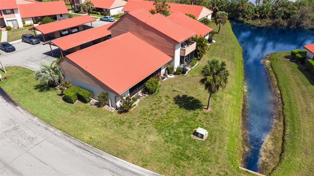 An aerial view shows a multi-unit residential building with red roofs near a small canal — 6535 DRAW LANE UNIT 85, SARASOTA, FL