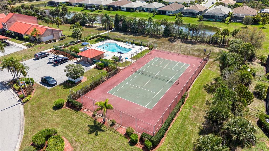 An aerial view shows a tennis court, a swimming pool, and a parking lot — 6535 DRAW LANE UNIT 85, SARASOTA, FL
