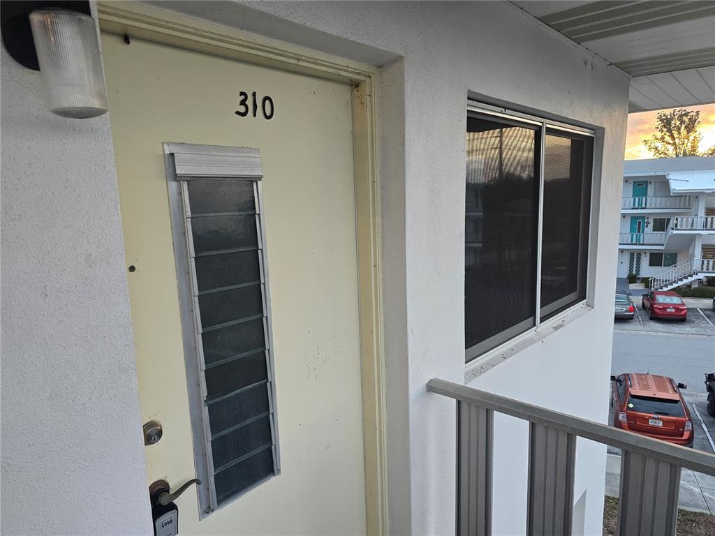 A light-colored door numbered 310 features a vertical louvered window and a keypad lock — 11100 86TH AVENUE UNIT 310, SEMINOLE, FL