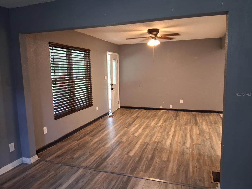 An empty room with gray walls, wood-look flooring, a ceiling fan, and a side door — 10628 CR 771, WEBSTER, FL