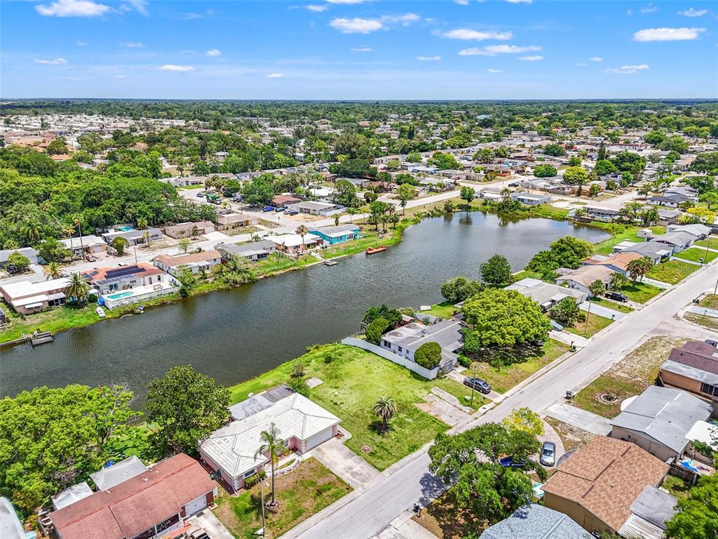 An aerial view shows residential houses surrounding a central lake in a suburban neighborhood — 7211 ASHWOOD DRIVE, PORT RICHEY, FL