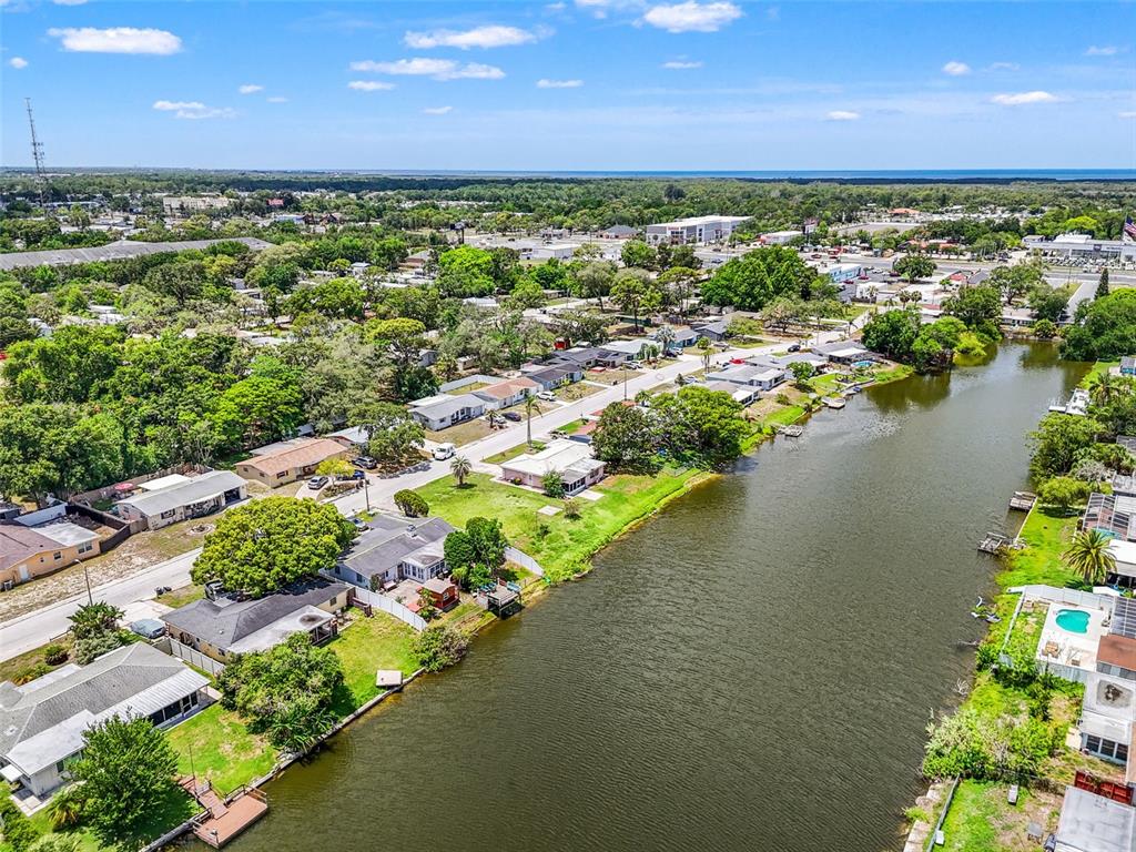 An aerial view shows a residential street lined with houses along a narrow canal — 7211 ASHWOOD DRIVE, PORT RICHEY, FL