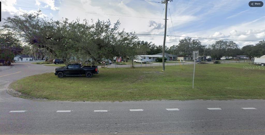 A vacant grassy lot with a large tree and a parked truck near a road — N/A, POLK CITY, FL