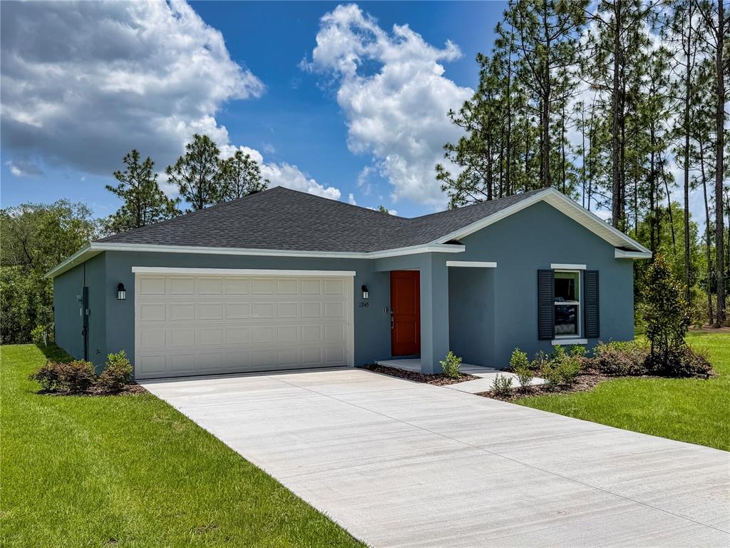 A single-story house with blue stucco siding, a two-car garage, and a red front door — 13145 SW 83RD TERR ROAD, OCALA, FL