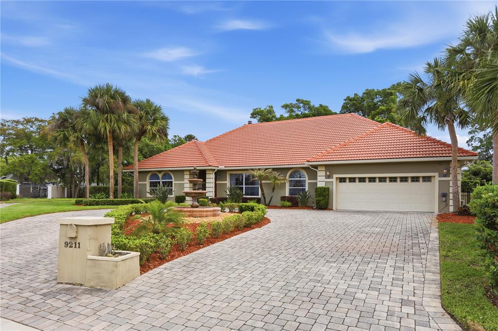 A single-story house with a red tile roof, a paved driveway, and a front fountain — 9211 HIDDEN BAY LANE, ORLANDO, FL