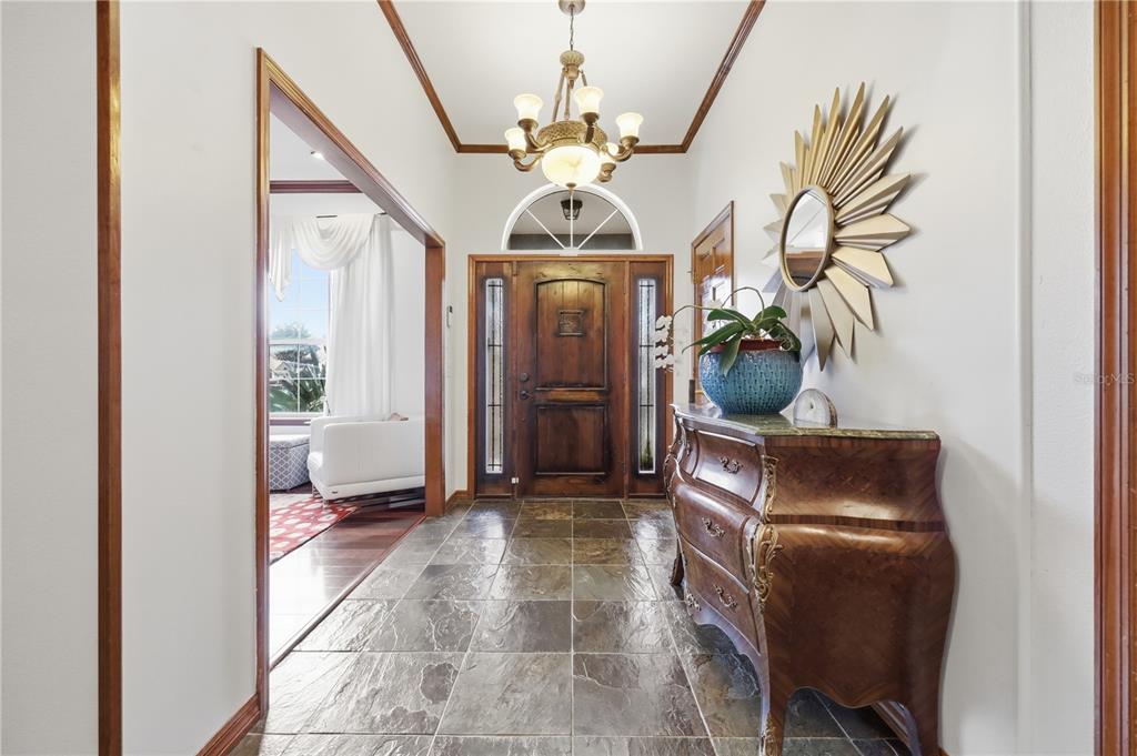A red wooden front door with a decorative grille sits under a covered entryway — 9211 HIDDEN BAY LANE, ORLANDO, FL