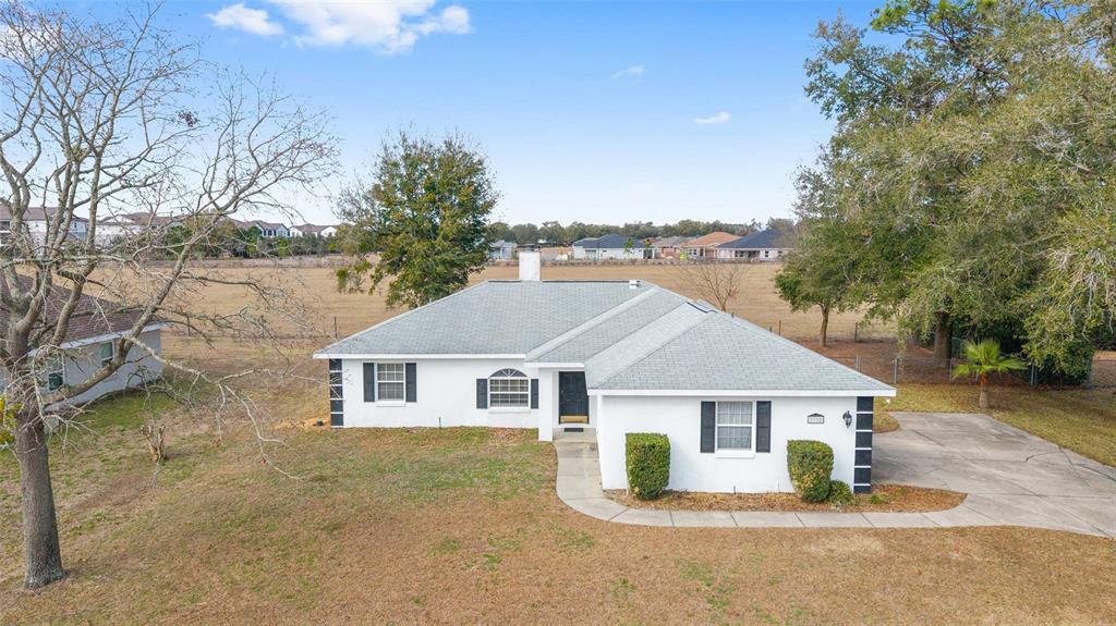 An aerial view of a white, single-story house with a gray roof and a driveway — 3332 NW 50TH COURT, OCALA, FL