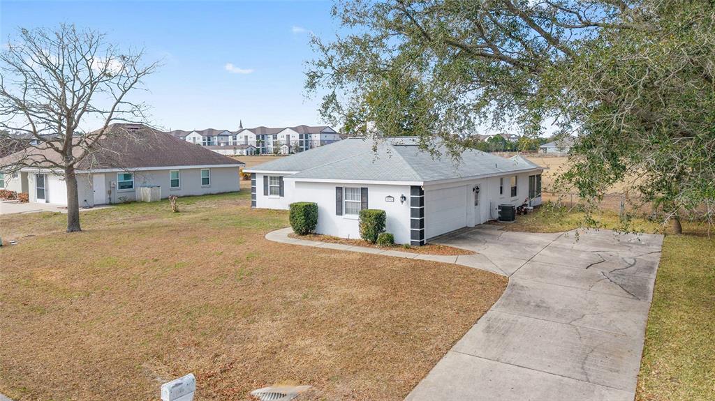 A white single-story house with a concrete driveway and a large tree in the yard — 3332 NW 50TH COURT, OCALA, FL