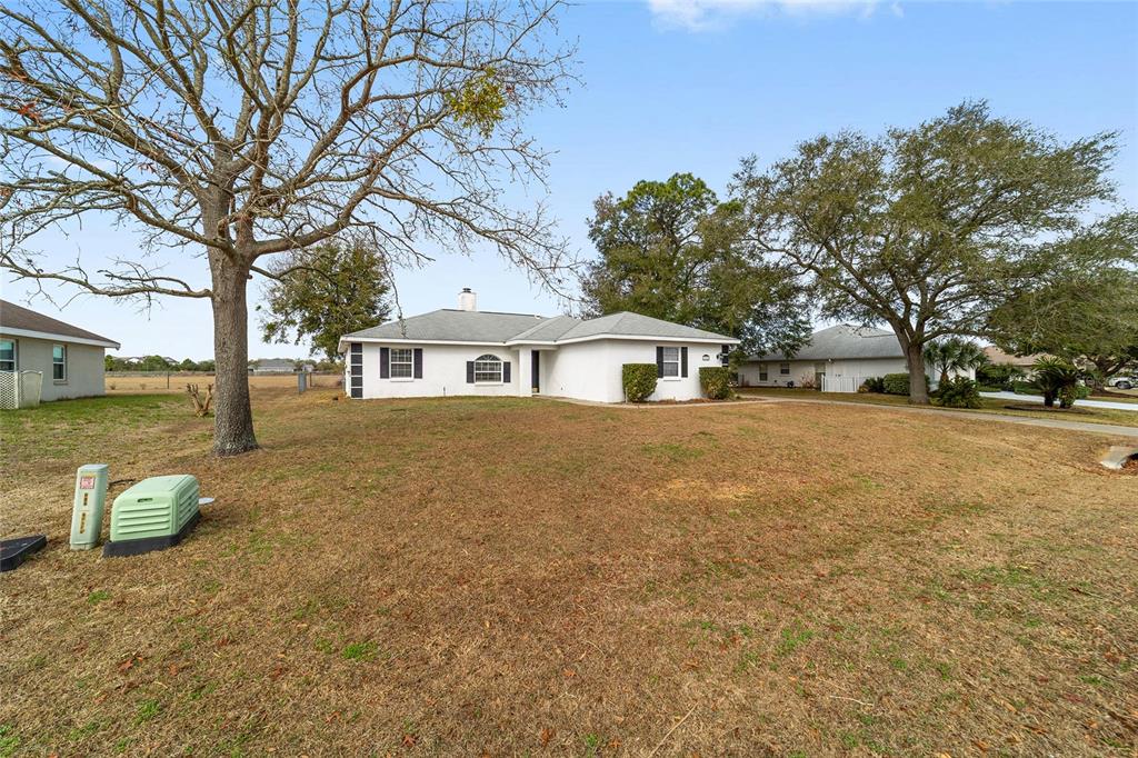 A white single-story house with a gray roof sits on a large, dry grassy lot — 3332 NW 50TH COURT, OCALA, FL