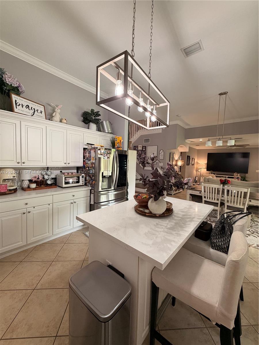 A kitchen features white cabinets, a quartz-topped island with seating, and a large pendant light — 2116 NE 38th Rd # 2116, Homestead FL 33033, HOMESTEAD, FL