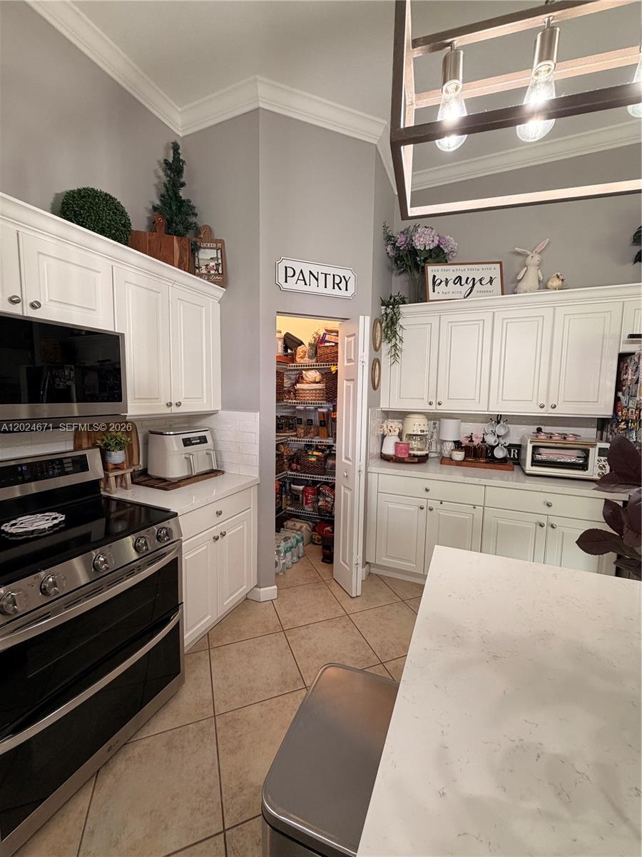 A kitchen features white cabinets, a walk-in pantry, stainless steel appliances, and tile flooring — 2116 NE 38th Rd # 2116, Homestead FL 33033, HOMESTEAD, FL