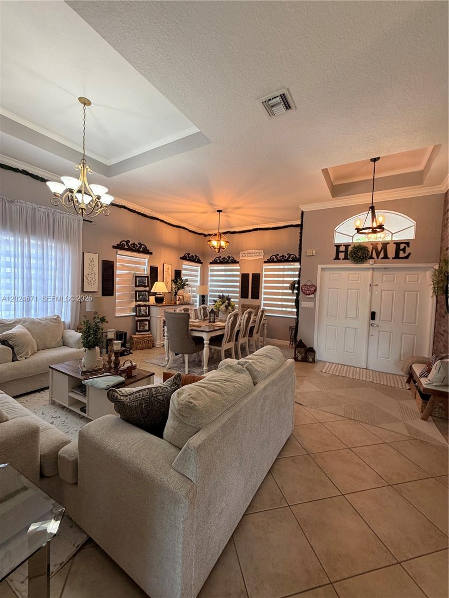This open-concept living and dining area features tile flooring, tray ceilings, and neutral furniture — 2116 NE 38th Rd # 2116, Homestead FL 33033, HOMESTEAD, FL