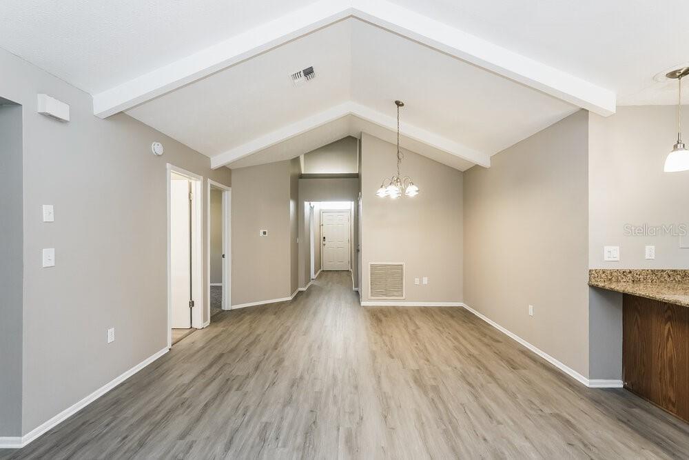 A room with vaulted ceilings, light wood-look flooring, and a chandelier over the dining area — 13403 WOODWARD DRIVE, HUDSON, FL