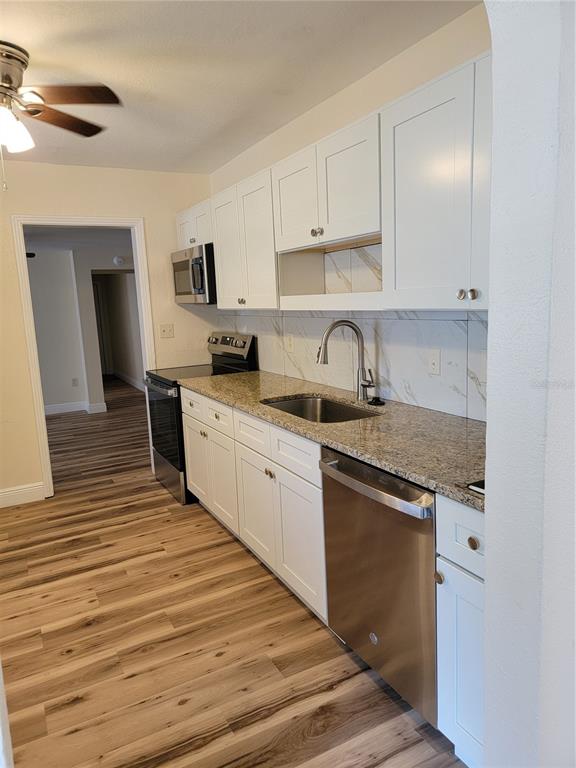 A kitchen features white cabinets, granite countertops, stainless steel appliances, and wood-look flooring — 542 & 540 S CLAYTON AVENUE, LAKELAND, FL