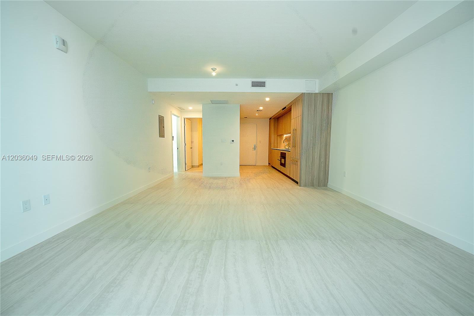 An open-concept living area features light-colored tile flooring and a modern kitchen with wood cabinetry — 77 SE 5TH ST # 1607, Miami FL 33131, MIAMI, FL