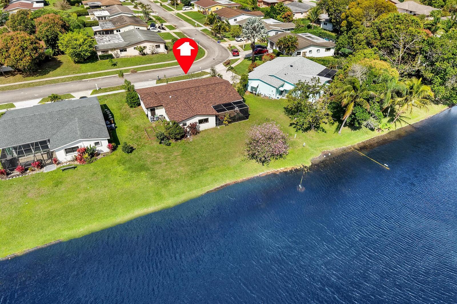 An aerial view shows a single-story house with a brown roof situated beside a lake — 14592 Country Side Lane, Delray Beach FL 33484, DELRAY BEACH, FL