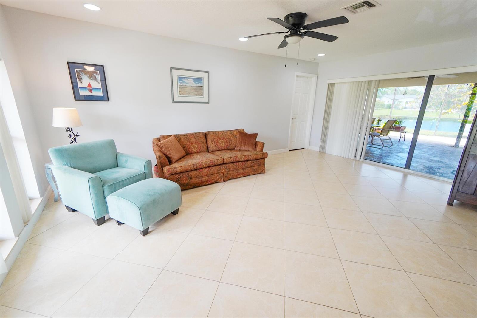 A living room features light tile floors, a patterned sofa, and a blue armchair — 14592 Country Side Lane, Delray Beach FL 33484, DELRAY BEACH, FL