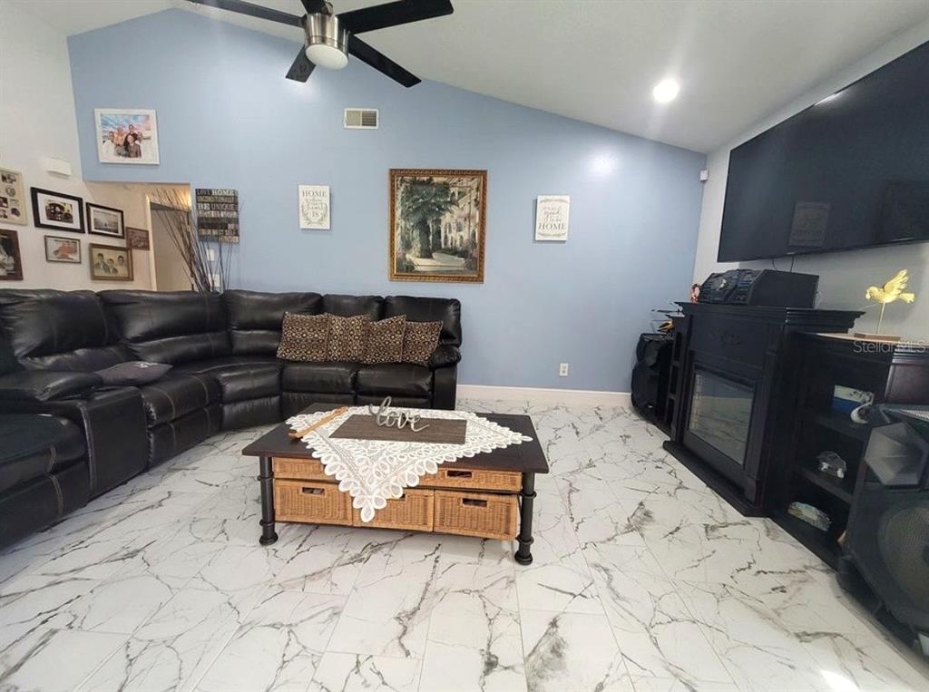 A living room features a black sectional sofa, a coffee table, and a fireplace — 2609 MILL RUN BOULEVARD, KISSIMMEE, FL