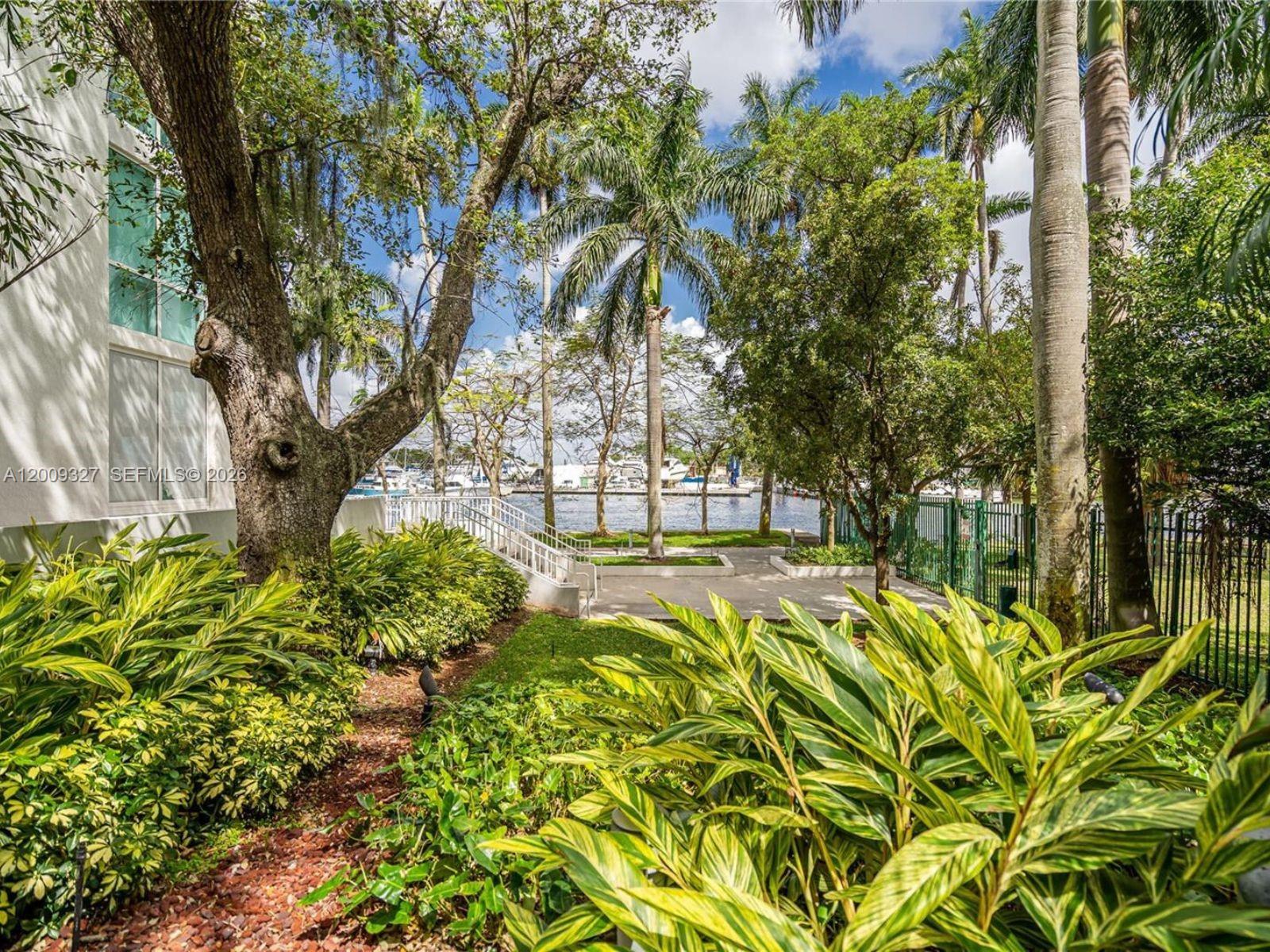 A view of a landscaped garden with palm trees, a walkway, and a waterfront marina — 1861 NW S River Dr # 1408, Miami FL 33125, MIAMI, FL