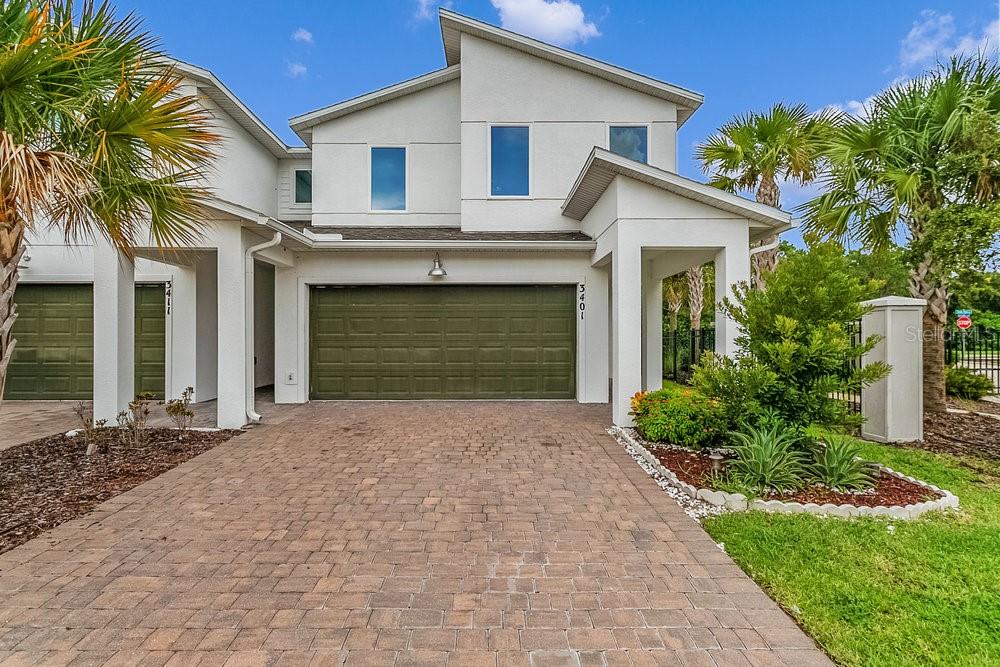 A two-story house exterior features a paved driveway, a green garage door, and palm trees — 3401 BEAU ROAD, KISSIMMEE, FL