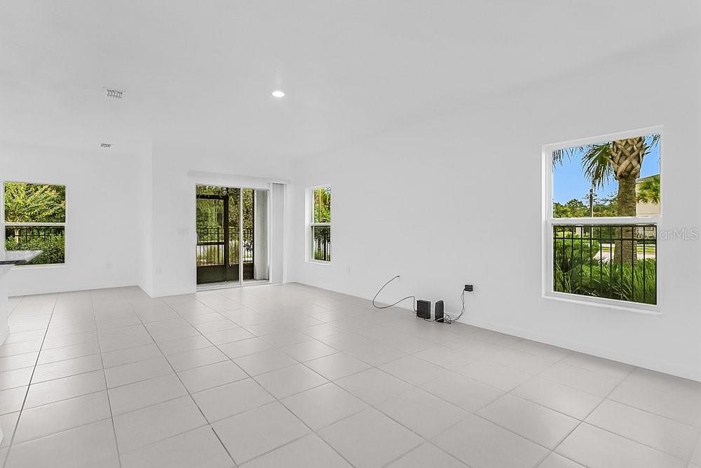 An empty room with white walls, light tile flooring, sliding glass doors, and several windows — 3401 BEAU ROAD, KISSIMMEE, FL
