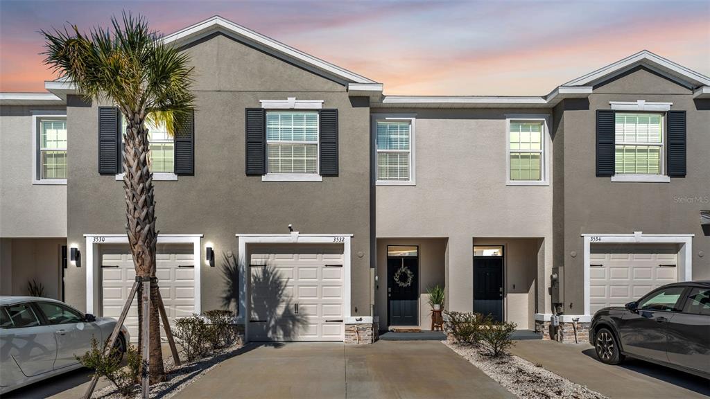 A row of three two-story townhomes with gray stucco facades, garages, and paved driveways — 3532 WHITE DANDELION COURT, PLANT CITY, FL