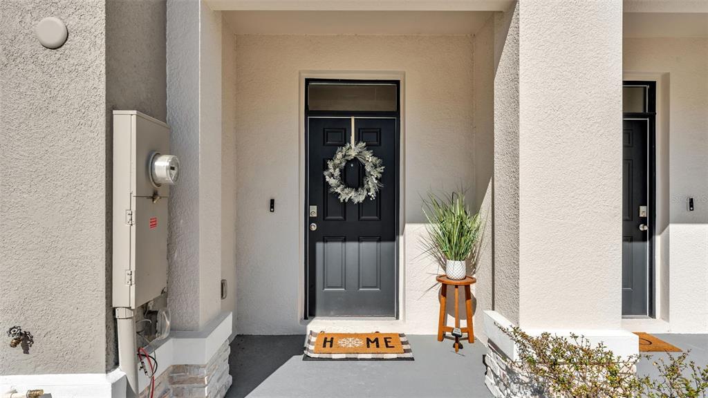 An exterior view of a home entrance featuring a dark door with a wreath — 3532 WHITE DANDELION COURT, PLANT CITY, FL