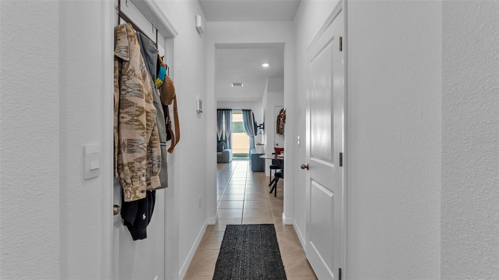 A hallway with tile flooring leads to an open living area with a glass door — 3532 WHITE DANDELION COURT, PLANT CITY, FL