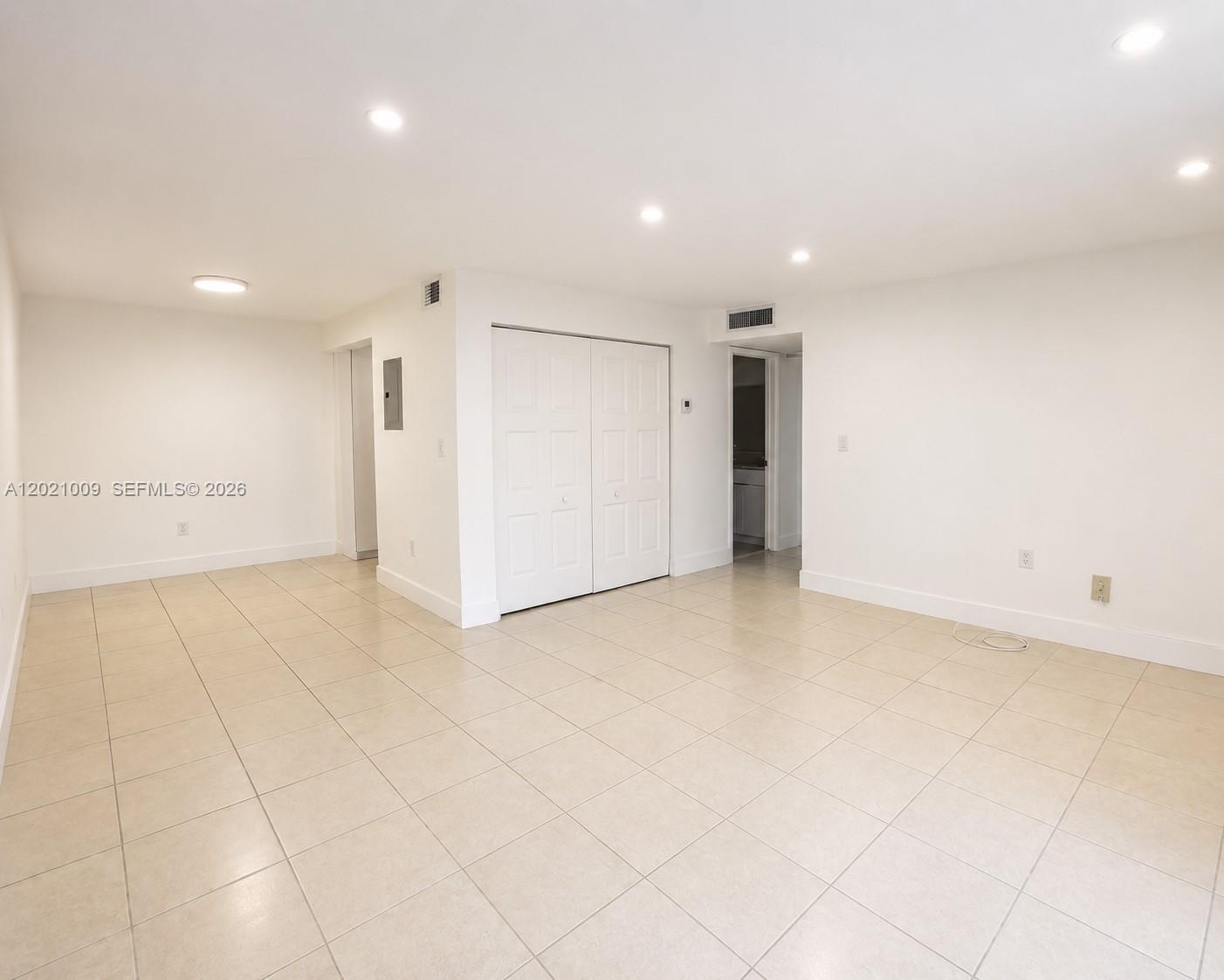 An empty room features white walls, recessed lighting, and light-colored square floor tiles — 7160 Fairway Dr # J16, Miami Lakes FL 33014, MIAMI LAKES, FL