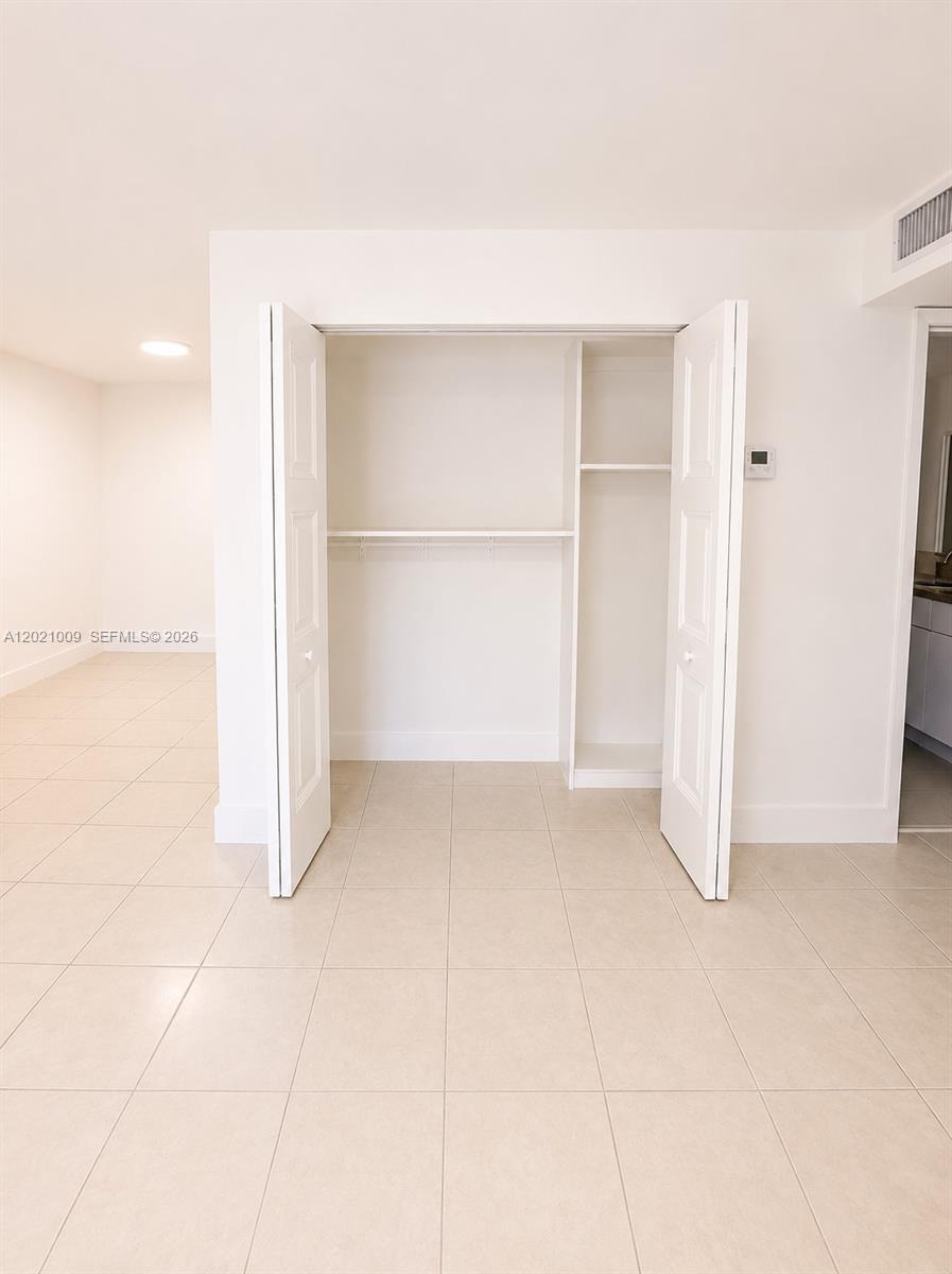 A white closet with shelving sits in a room with light-colored tile flooring — 7160 Fairway Dr # J16, Miami Lakes FL 33014, MIAMI LAKES, FL